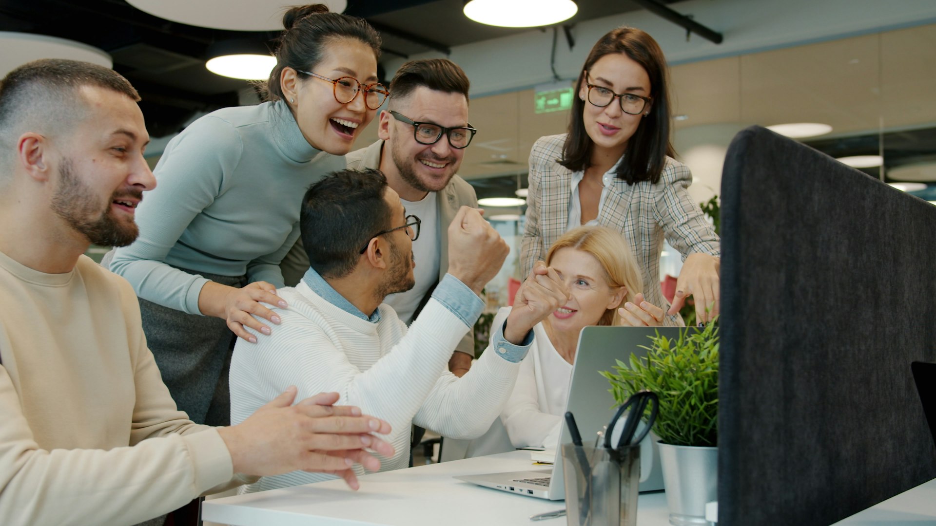 Diverse team celebrating success at office desk.